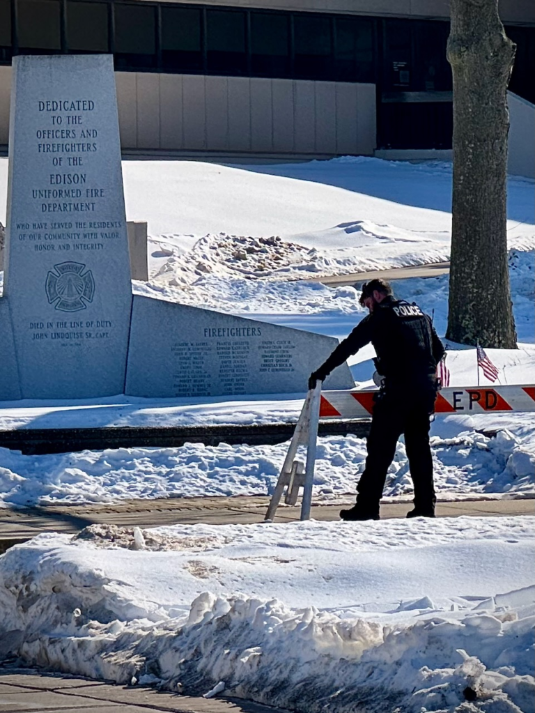 An Edison police officer sets up barricades near the municipal building ahead of a student-led anti-ICE rally