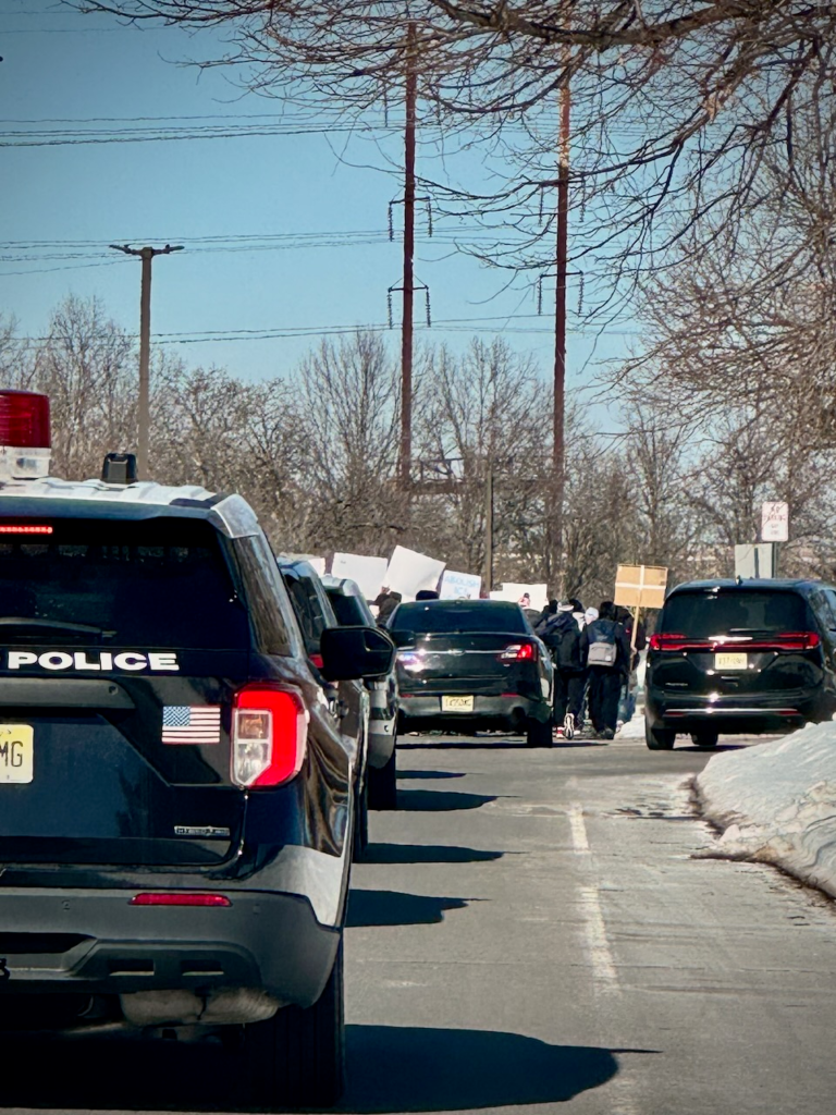 Edison police vehicles escort Edison High School students during a peaceful anti-ICE march through township streets